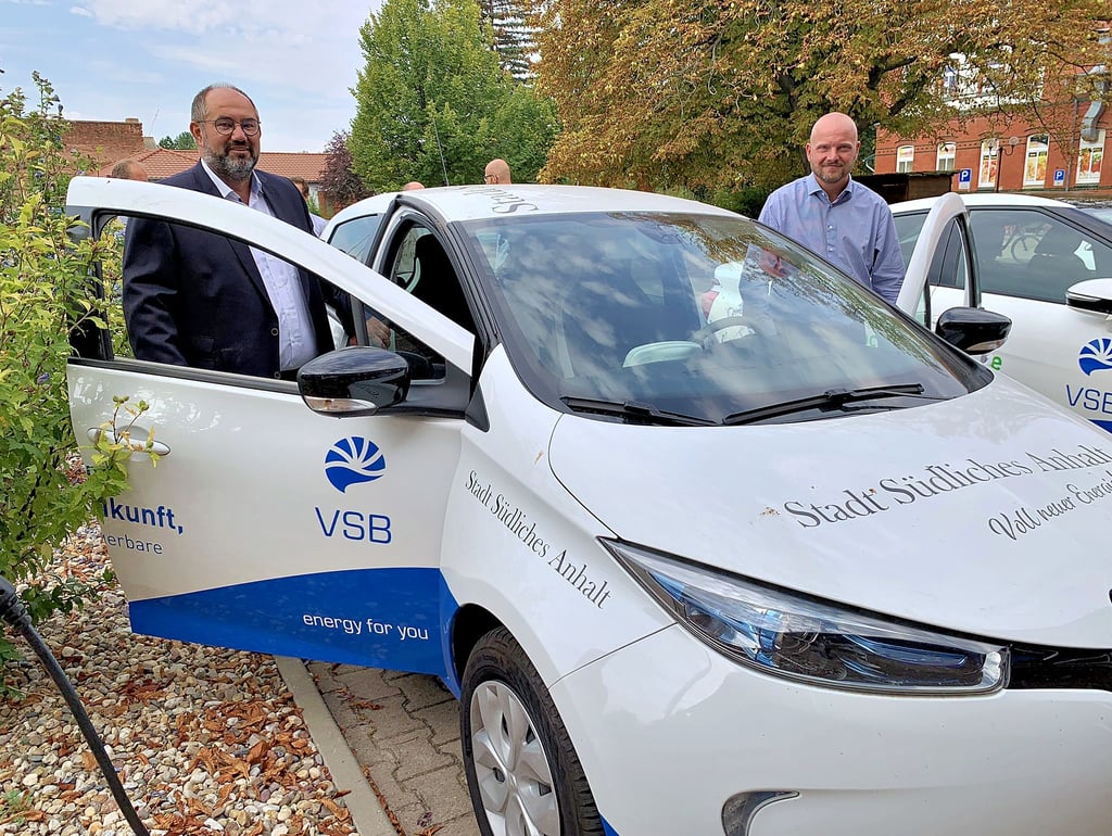 Bürgermeister Thomas Schneider (l.) und Fachbereichsleiter Maik Kuhn (r.) stehen am elektrischen Dienstwagen.