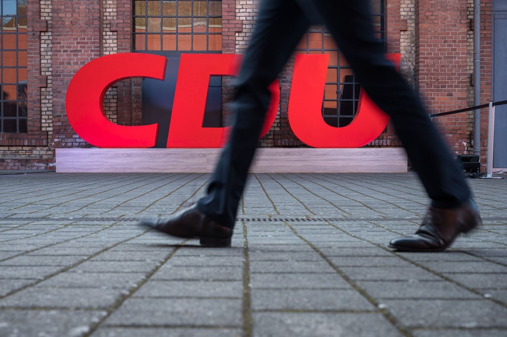 Ein Passant geht an einem Logo der CDU vorbei.