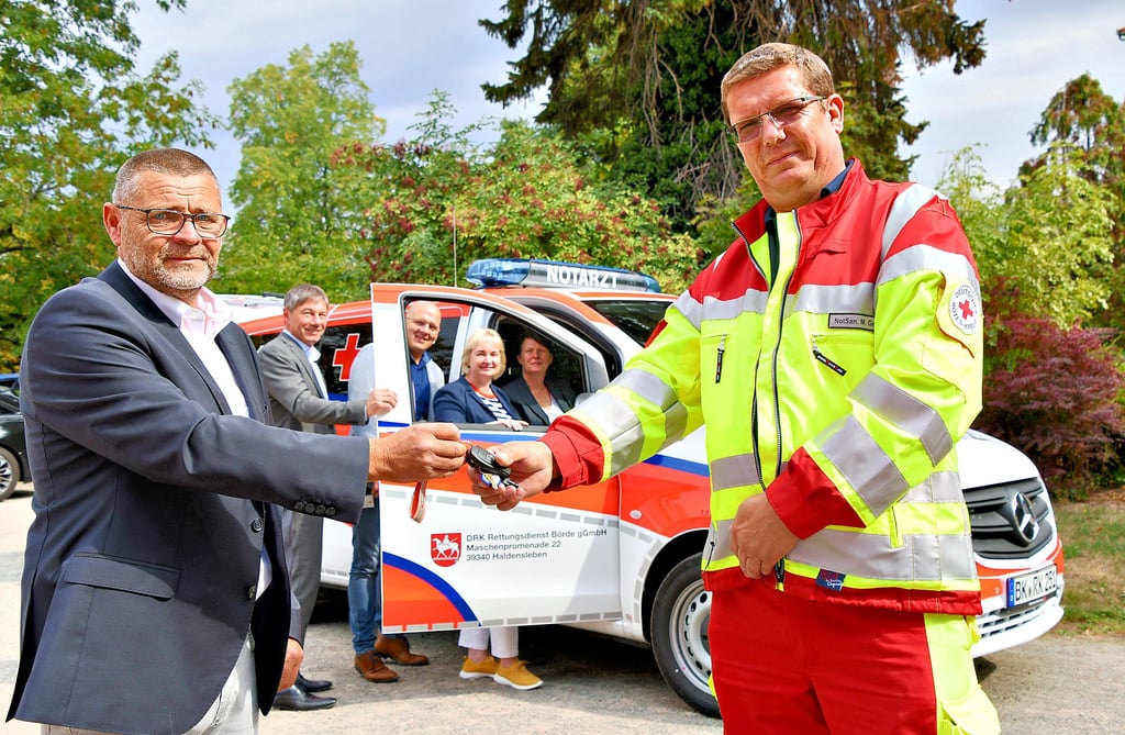 Ein nagelneues Notarzteinsatzfahrzeug übergibt Ralf Schmidt (vorn; l.), Leiter vom DRK-Rettungsdienst Börde, an Notfallsanitäter Marko Gerono vom Team der Rettungswache in Erxleben. Das Fahrzeug an der Rettungswache in Erxleben bestaunen auch Ralf Kürbis (hinten; v.l.), Vorsitzender des Vorstandes, Jens Sips, Sachgebietsleiter Rettungsdienst beim Landkreis Börde, Corinna Sladky, Amtsleiterin für Brand- und Katastrophenschutz im Landkreis Börde und Sylvia Franke, stellvertretende Vorstandsvorsitzende.