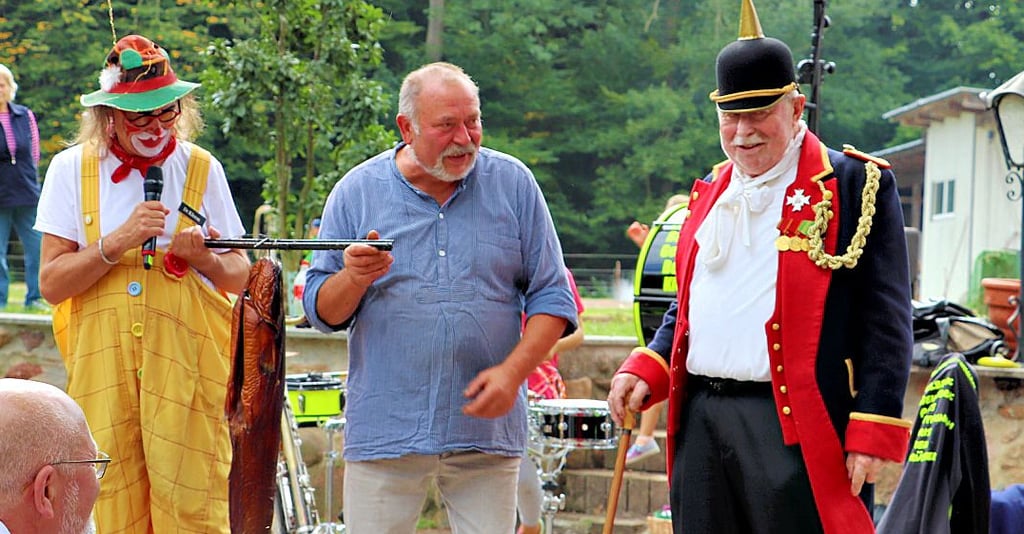 Bei der „amerikanischen Versteigerung“ war ein geräucherte Wels Objekt der Begierde. Clown Lulu, Uwe Marx und der „Alte Fritz“ (v. li.) präsentierten den Fisch.