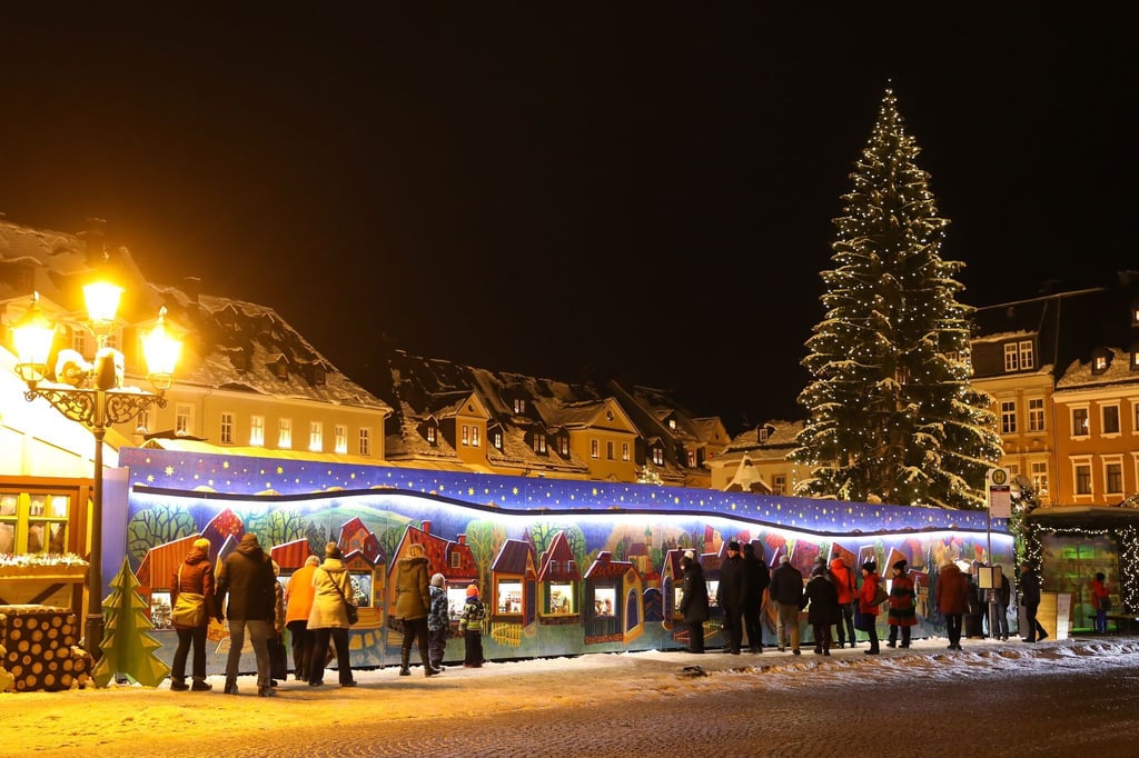 Passanten stehen vor der "Wichtelstadt" auf dem Annaberger Weihnachtsmarkt.