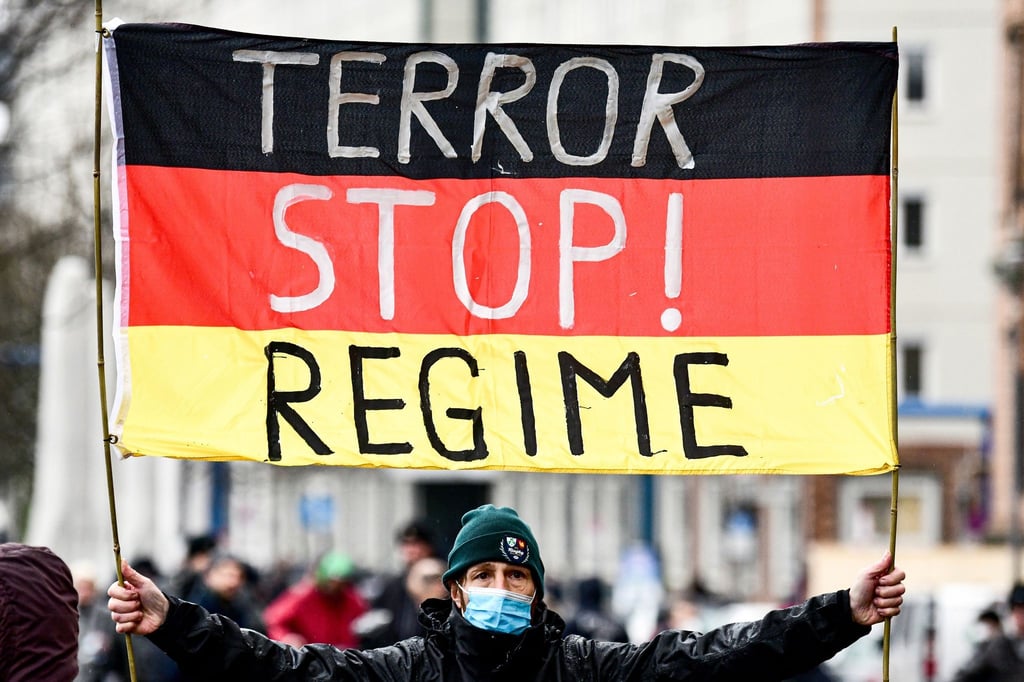 Ein Teilnehmer hält eine Deutschland-Fahne mit Schriftzug bei einer Demonstration gegen die Corona-Politik.