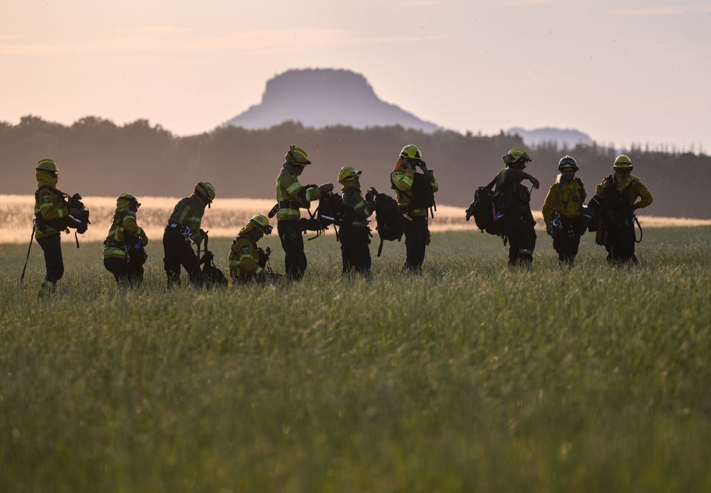 Freiwillige Feuerwehrleute des Internationalen Katastrophenschutz Deutschland „@fire“ stehen nach dem Einsatz auf einer Wiese.
