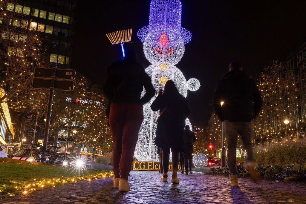 Passanten gehen an einer Schneemann-Illumination nach dem Start der Weihnachtsbeleuchtung am Kudamm-Tauentzien vorbei.