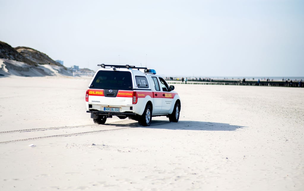 Ein Einsatzfahrzeug der DLRG Wasserrettung fährt über einen Strand.