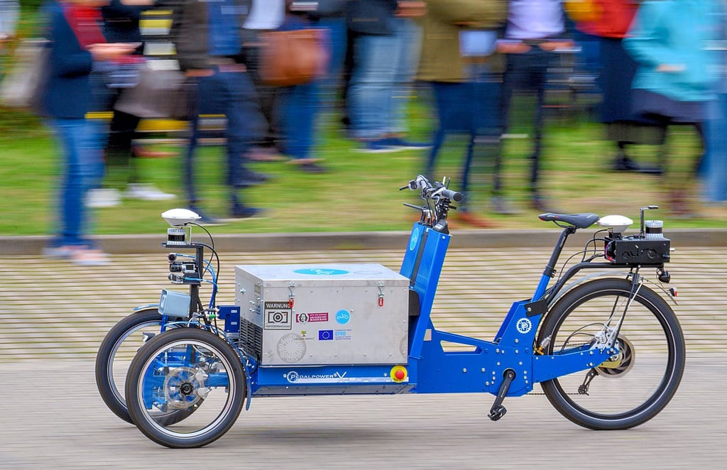Das autonome Lastenrad „AuRa“ fährt auf dem Campus der Otto-von-Guericke Universität Magdeburg an den Gästen der Abschlussdemonstration vorbei.