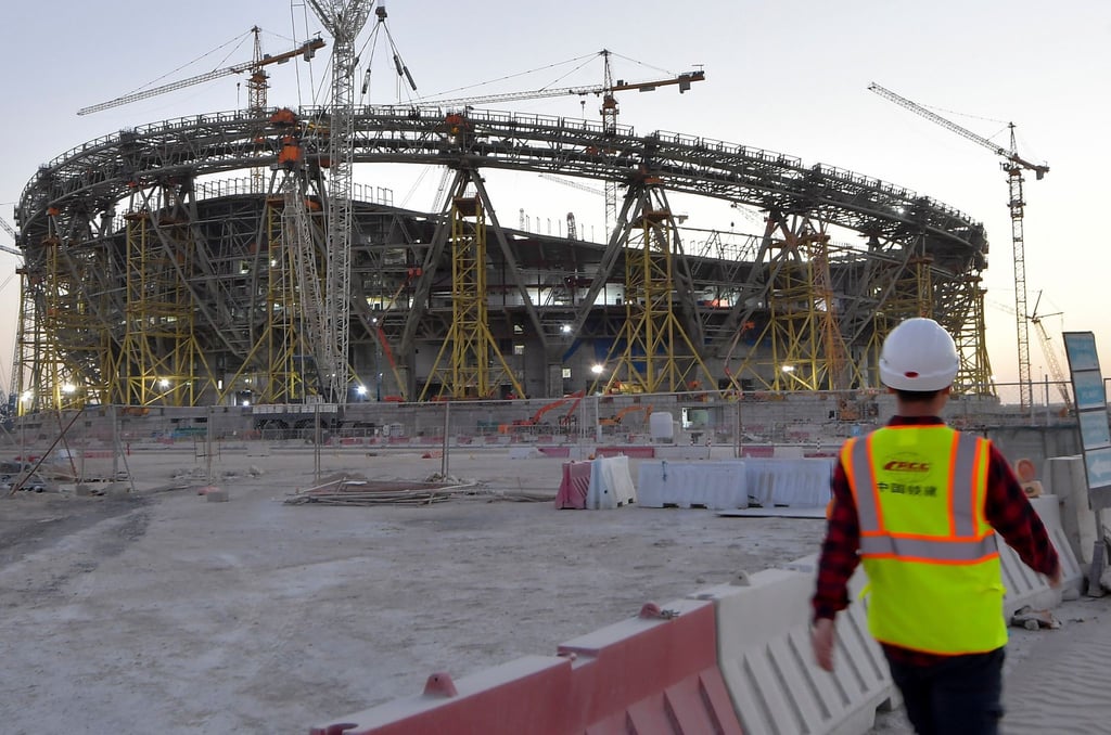 Ein Mann mit Schutzhelm und Schutzweste geht über die Baustelle des Lusail Iconic Stadiums.