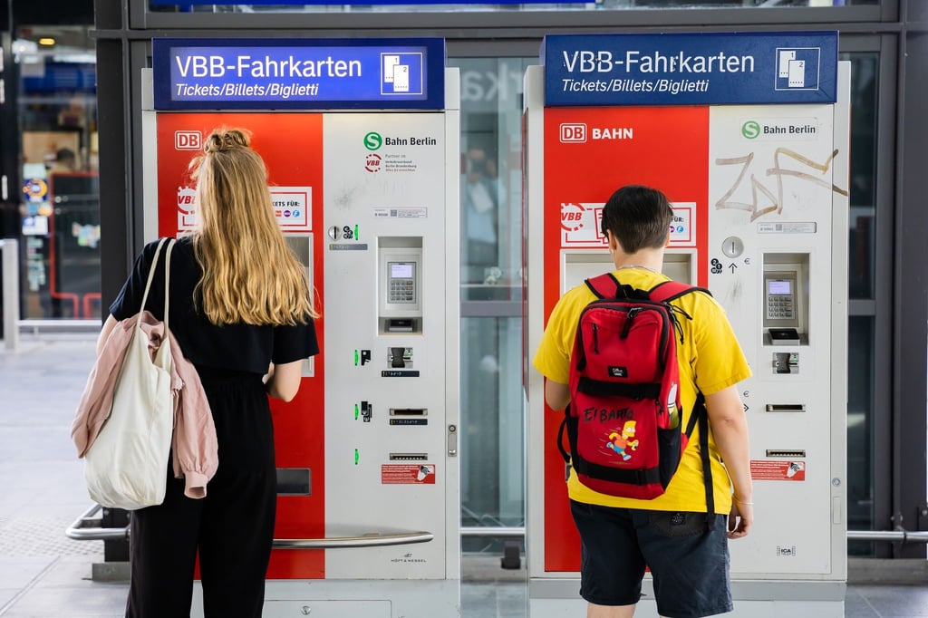 Zwei Fahrgäste kaufen Fahrscheine an einem Automaten.