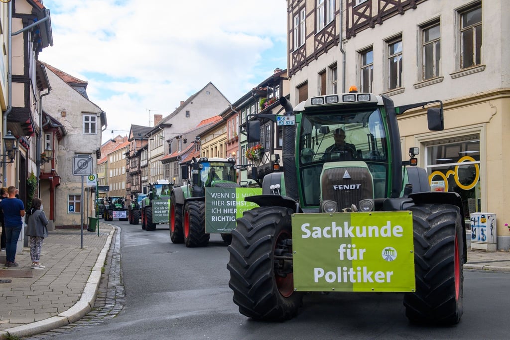 Landwirte fahren mit ihren Traktoren in der Innenstadt von Quedlinburg an Passanten vorbei.