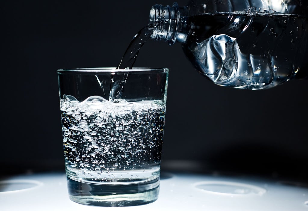 Ein Glas wird mit Mineralwasser befüllt.