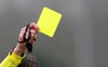 Symbolfoto - Ein Schiedsrichter zeigt die Gelbe Karte.