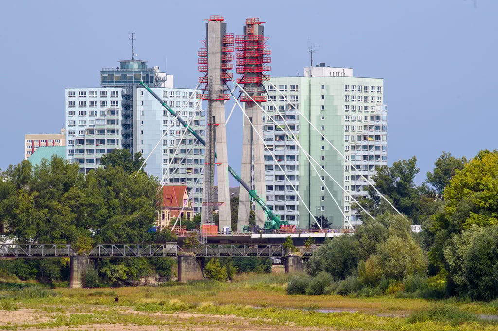 Blick auf die im Bau befindliche Pylonbrücke an der Alten Elbe in Magdeburg, davor die stillgelegte Eisenbahnbrücke, dahinter die Hochhäuser auf dem Werder.