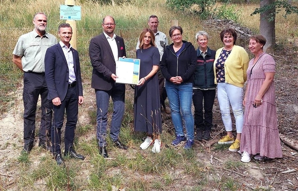Teffen im Hohen Holz: Landrat Martin Stichnoth übergibt eine Urkunde an Anke Goltz, Leiterin der Reiterstein-Grundschule Hornhausen. Die Schüler und Lehrer hatten sich in besonderer Weise für den Wald engagiert und einen Spendenlauf organisiert.