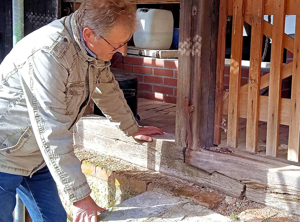 Ralf Lindemann begutachtet die Holzschwelle am Eingang zum Erdgeschoss des Brunnenhauses.