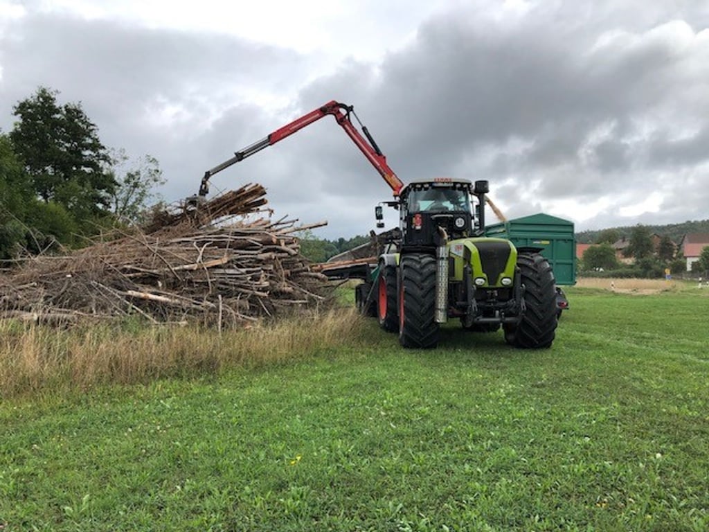 Aus Holz werden Hackschnitzel gehäckselt. Das Holz wird mit einem Kran und einer Zange in den Häcksler geschoben.