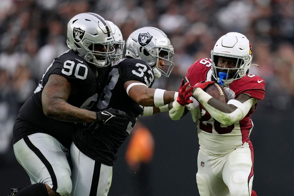 Eno Benjamin (r) von den Arizona Cardinals in Aktion mit Roderic Teamer (33) und Johnathan Hankins (90) von den Las Vegas Raiders.
