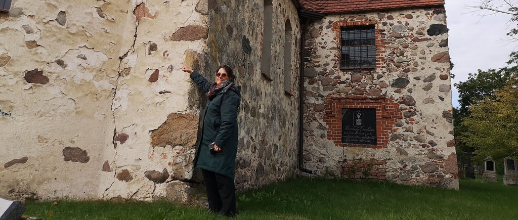 Yvonne Morselt deutet auf charakteristischen Riss in Mauerwerk der Kirche in Tylsen.