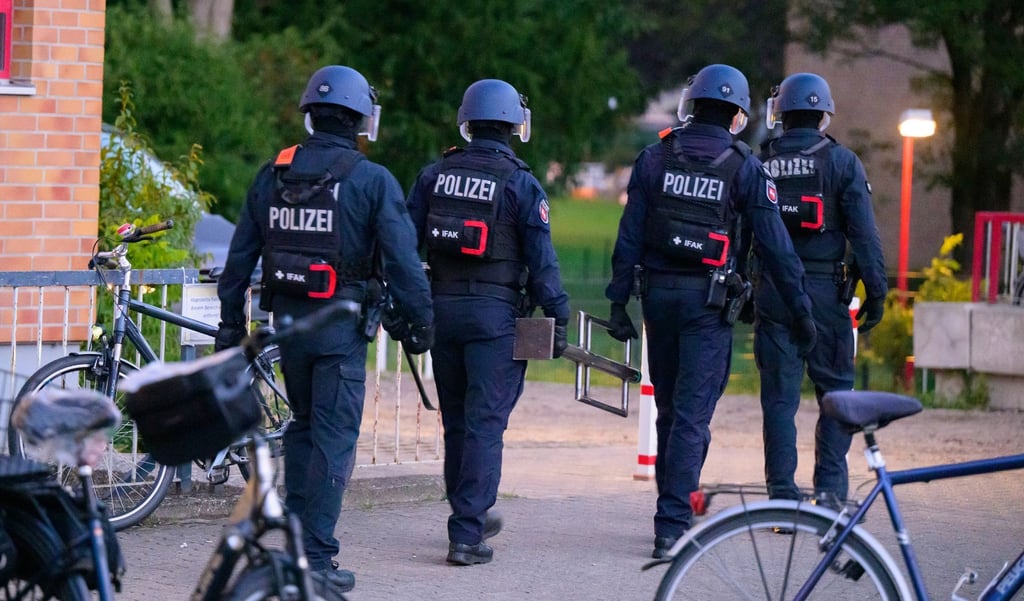 Polizisten verlassen nach einer Durchsuchung ein Wohngebiet.