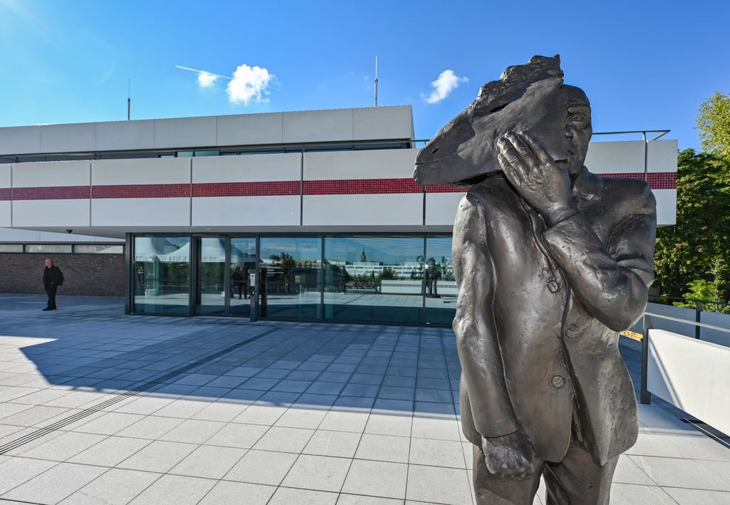 Die Bronzeskulptur „Maskenmann /Gesichtzeigen“ steht vor „Das Minsk Kunsthaus in Potsdam“.