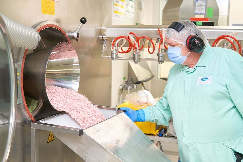 Ein Mitarbeiter von Pfizer betrachtet Paxlovid-Tabletten in einer Produktionsanlage.