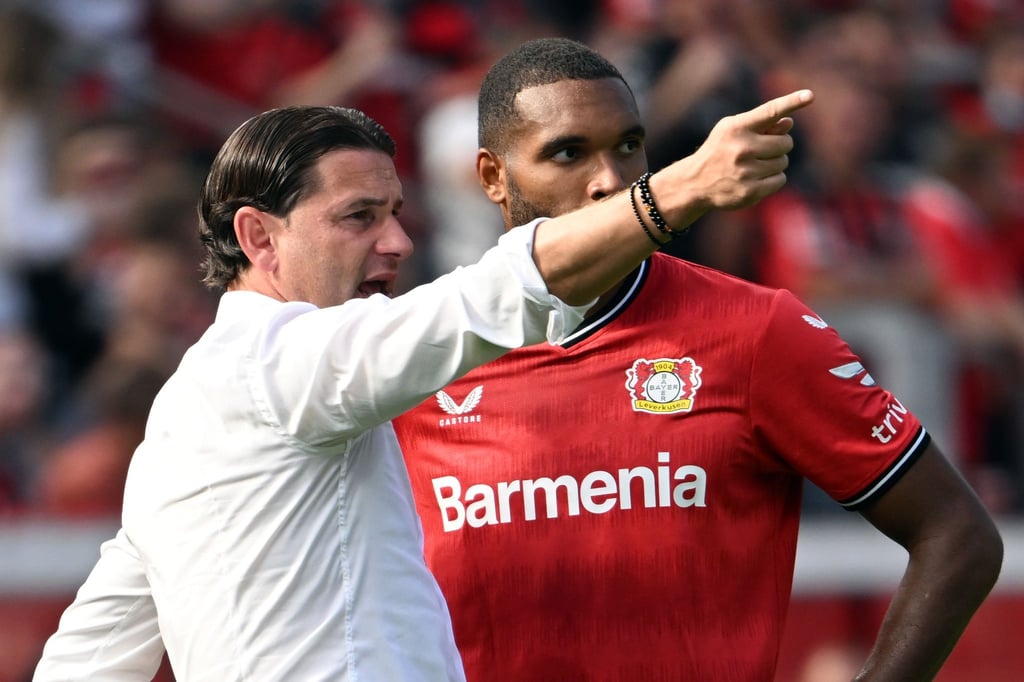 Leverkusens Trainer Gerardo Seoane (l) spricht an der Seitenlinie mit Jonathan Tah.