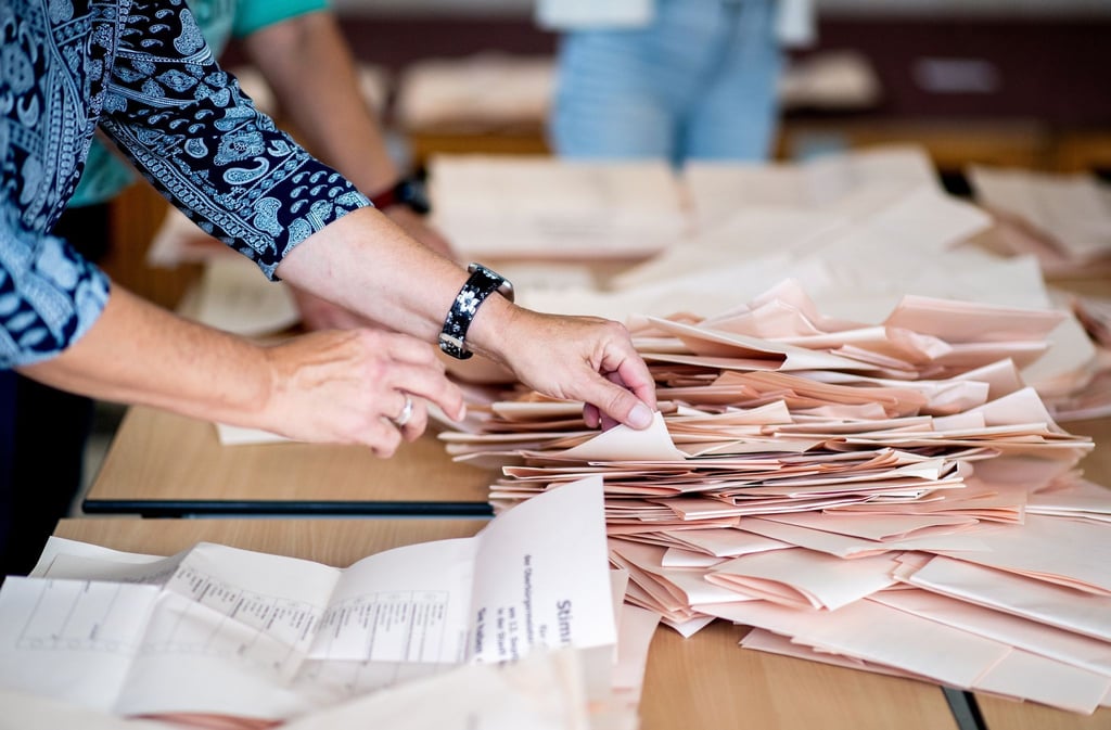 Eine Wahlhelferin sortiert in einem Wahllokal die Stimmzettel für die Auszählung.