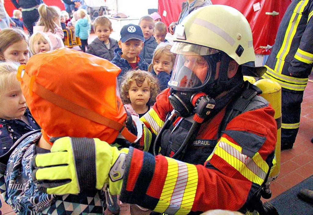 Einige der Sandmännchenkinder probierten bereitwillig die Fluchthaube aus, die ihnen der Fuerwehrmann unter Atemschutz aufsetzte.