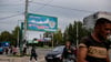 Menschen gehen in der von Russland unterstützten und von Separatisten kontrollierten Volksrepublik Luhansk in der Ostukraine an einem Plakat mit der Aufschrift „Unsere Wahl - Russland“ vorbei.