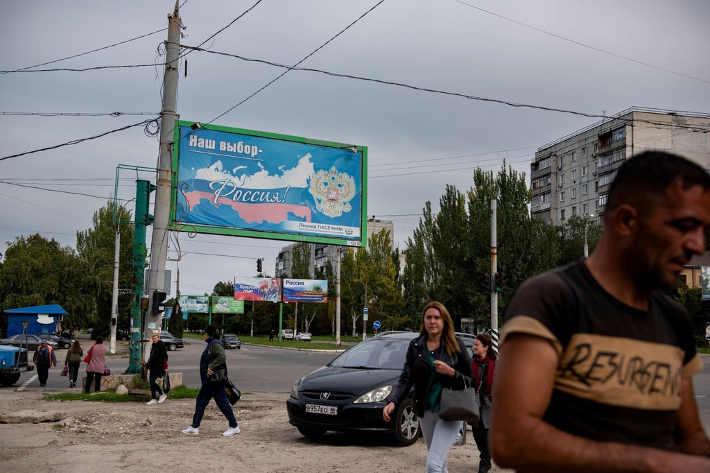 Menschen gehen in der von Russland unterstützten und von Separatisten kontrollierten Volksrepublik Luhansk in der Ostukraine an einem Plakat mit der Aufschrift „Unsere Wahl - Russland“ vorbei.