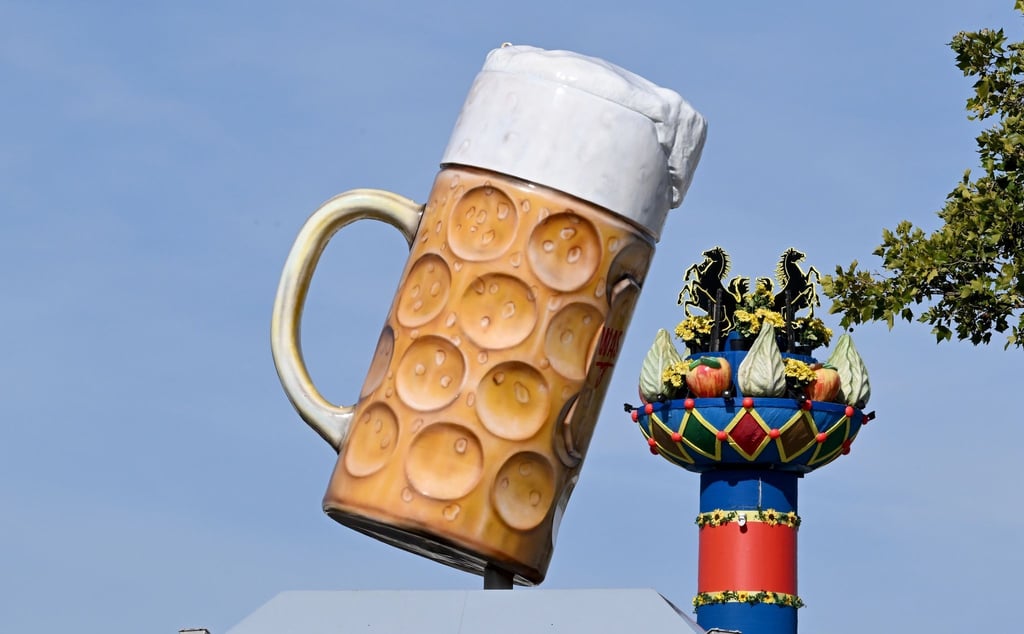 Ein riesiger Bierkrug steht am Eingang auf dem Festgelände Cannstatter Wasen, im Hintergrund steht die Fruchtsäule.