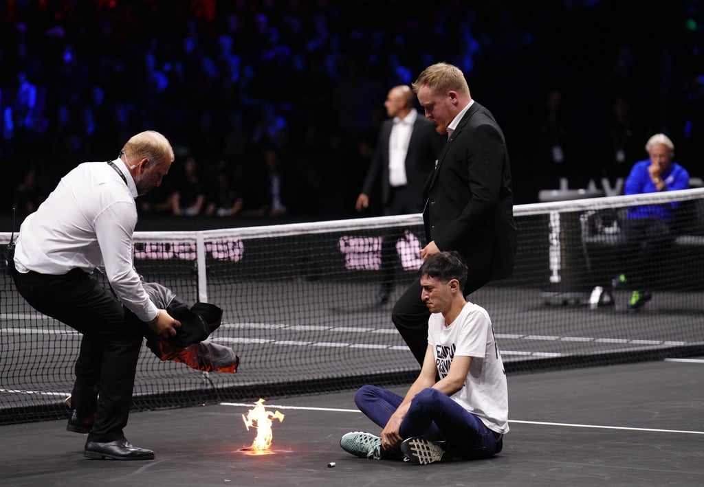 Match zwischen Tsitsipas und Schwartzman: In der Satzpause entzündet ein Demonstrant ein Feuer auf dem Spielfeld und gerät kurz in Brand.