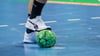 Ein Spieler hält einen Handball mit dem Fuß fest.