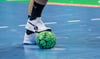 Ein Spieler hält einen Handball mit dem Fuß fest.