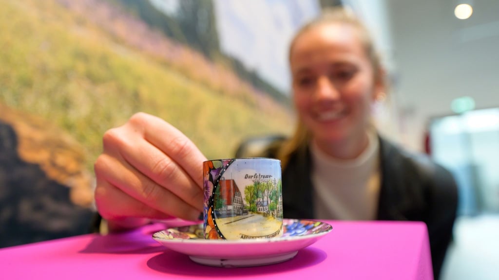 Nele Kröger, Künstlerische Leitung, hält in der Ausstellung eine kleine Tasse in den Händen.