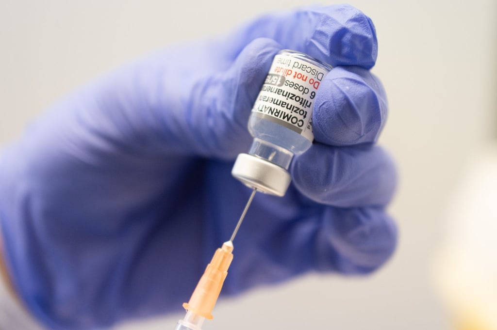 Ein Mitarbeiter zieht eine Spritze mit dem an die Omikron-BA.1-Variante angepassten Impfstoff Comirnaty von Biontech und Pfizer auf.
