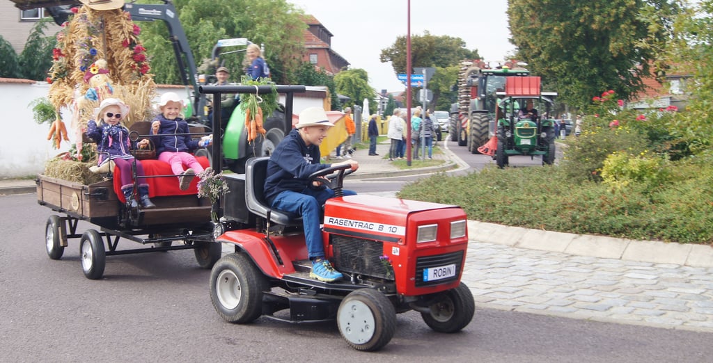 Robin Oelze ist mit seinem 8-km/h-Traktor und den Ernteprinzessinnen Fabienne und Mathilda unterwegs.n
