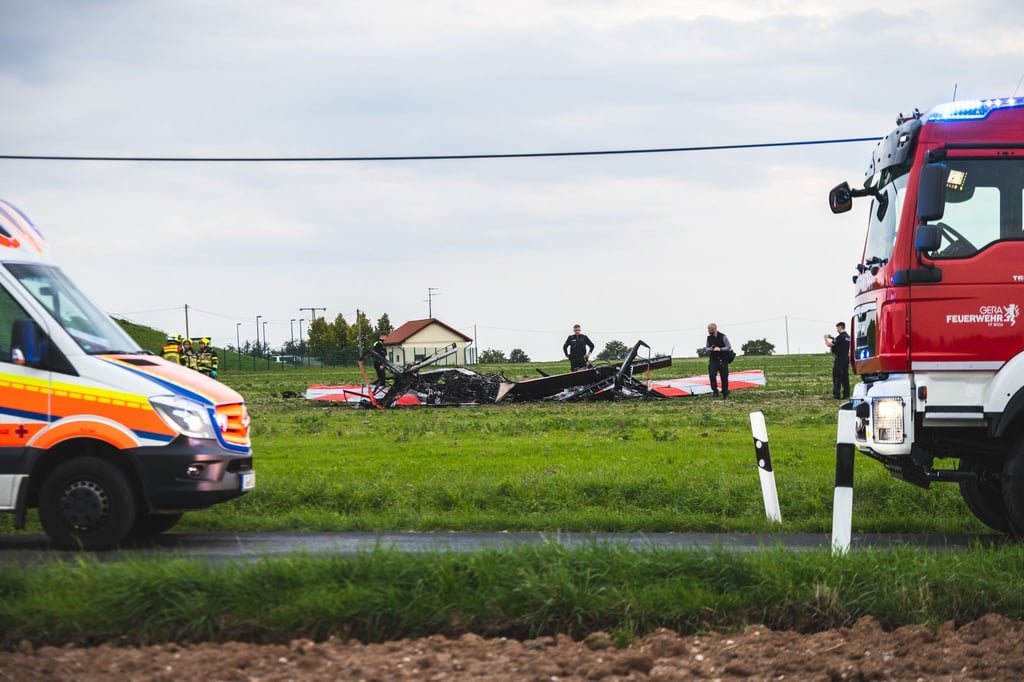 Einsatzkräfte der Polizei und Feuerwehr stehen an der Unglücksstelle, an der zwei Flugzeuge kollidiert und abgestürzt sind.