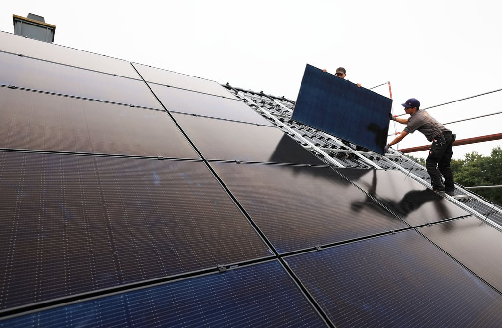 Handwerker montieren auf dem Dach eines Wohnhauses Solarmodule. In dieser Branche fehlen in und um Wernigerode viele Fachkräfte.