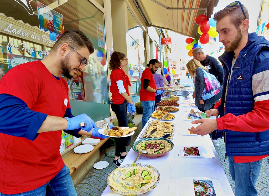 Jonathan Mulde (rechts) probierte am Samstag auf der Wilhelmstraße verschiedene Gerichte aus dem Orient aus, die ihm von Wael Aldali gereicht werden.