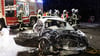 Feuerwehrleute stehen hinter dem Autowrack einer 54 Jahre alten Frau. Sie starb noch am Unfallort, nachdem ein Autofahrer frontal mit seinem Wagen in ihr Fahrzeug gerast war.