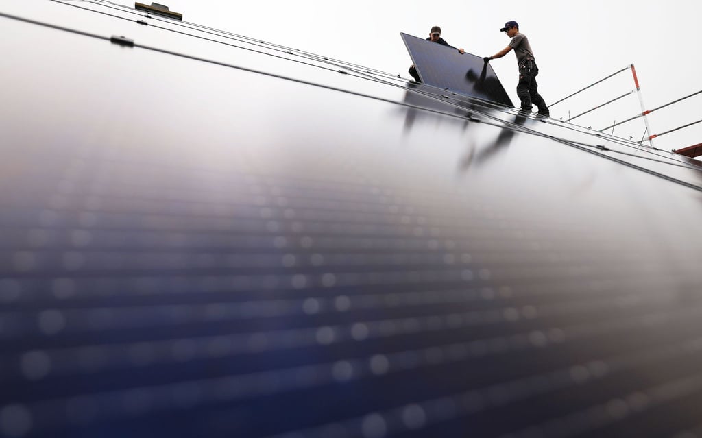 Handwerker montieren auf dem Dach eines Wohnhauses Solarmodule.