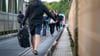 Fahrgäste laufen mit Koffern und anderem Gepäck über die Schleibrücke bei Lindaunis.