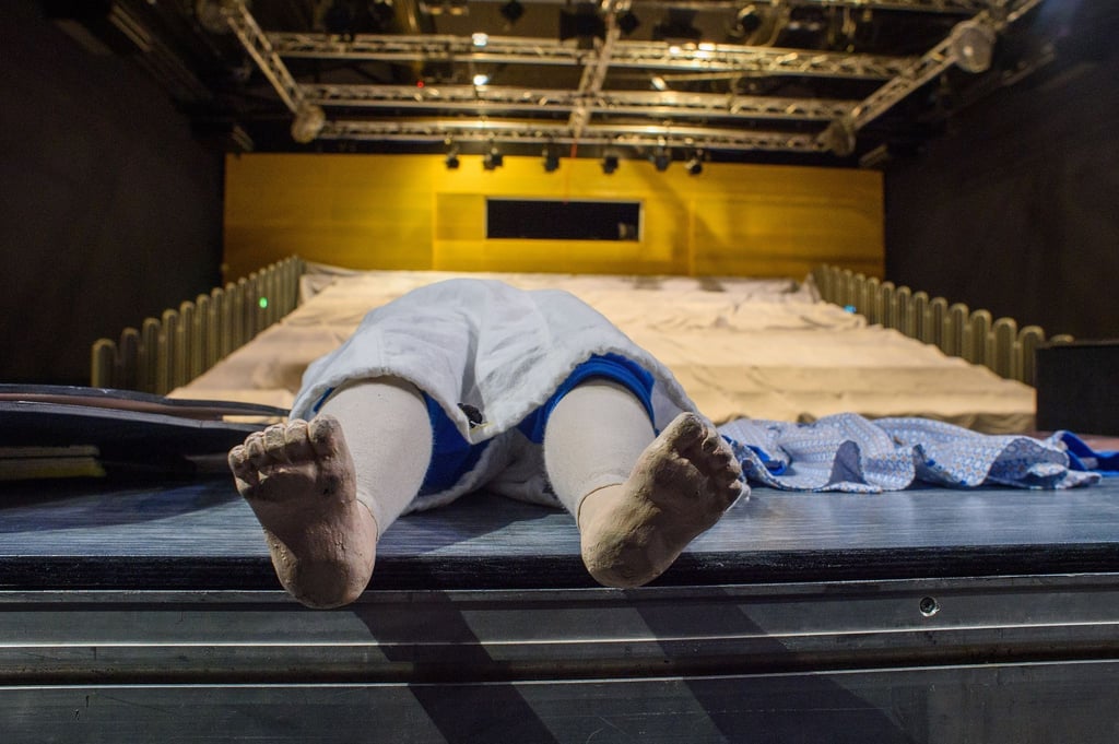 Eine Puppe liegt im großen Zuschauerraum des Puppentheaters auf der Bühne.