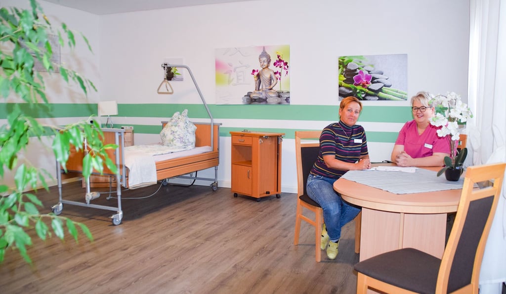 Pflegedienstleiterin Anja Liebing-Gröhl (links) und Vereinsvorsitzende Beatrice Tomszak sitzen am Tisch in einem der renovierten Zimmer. Diese haben Farbe und einen neuen Fußboden bekommen.