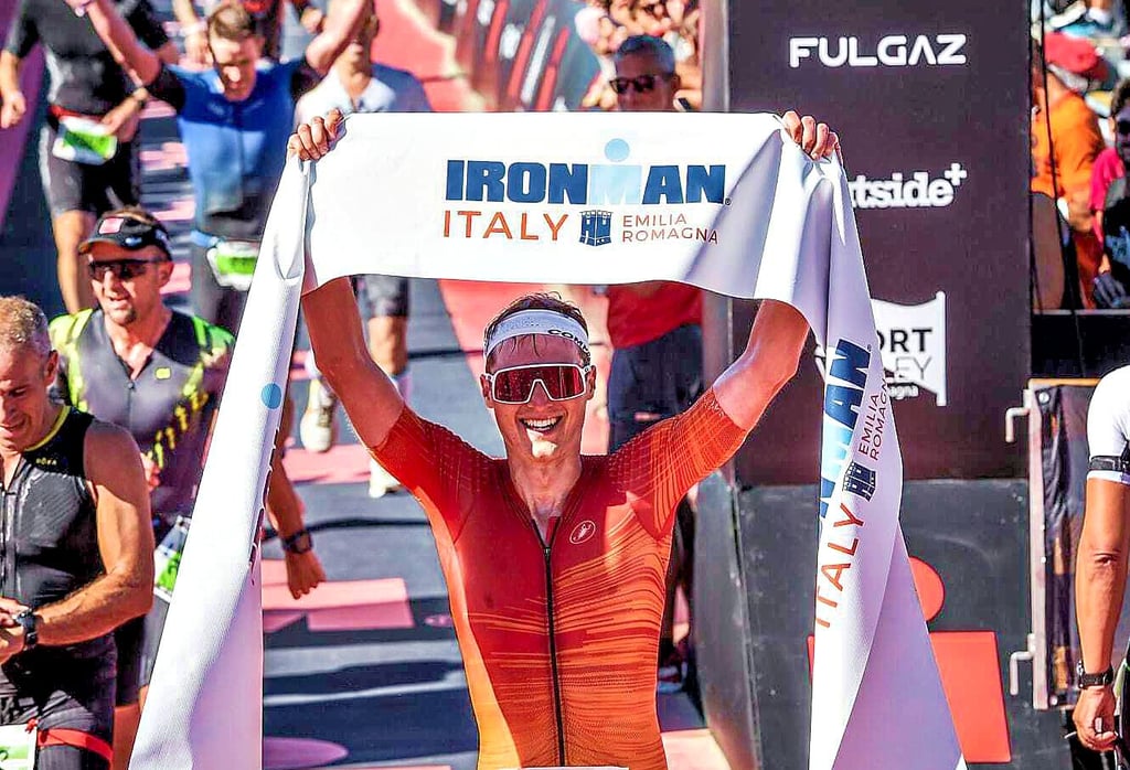 Michael Wegricht reckt nach seinem Einlauf überglücklich das Zielbanner in die Höhe. In einer Zeit von acht Stunden und elf Minuten hat der 27-Jährige gerade die Ziellinie des IronMan Italy Emilia-Romagna überquert.