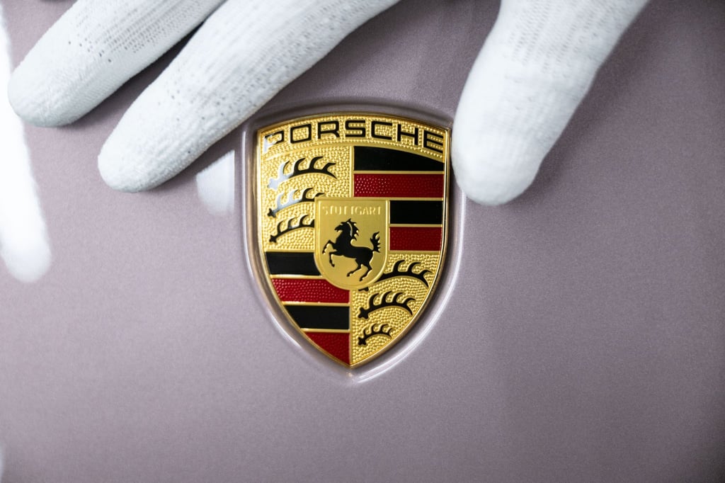 Ein Mitarbeiter der Porsche AG zeigt das Porsche-Logo.