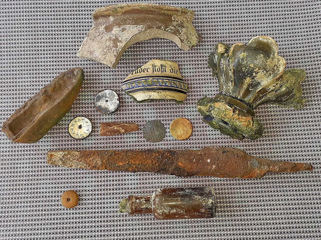 Die angeordneten Funde aus dem See: Gneis, Münzen, Scherben, Medizinflasche und Belemnit.