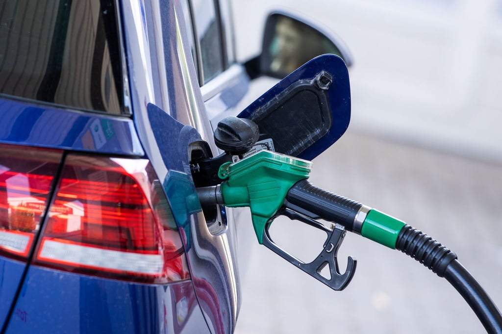 Eine Zapfpistole steckt an einer Tankstelle in einem Wagen.