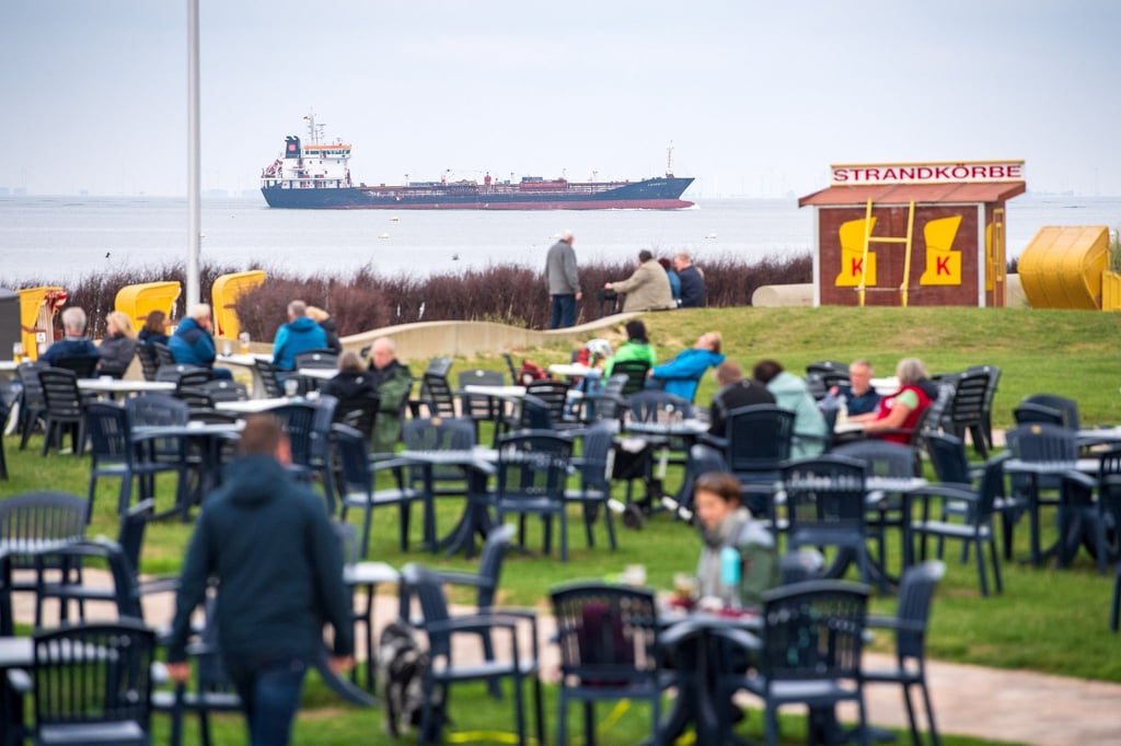Urlauber sitzen vor einem Café am Strand.
