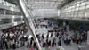Reisende stehen im Flughafen Düsseldorf in langen Warteschlangen an der Gepäckabgabe.